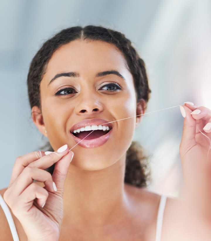 Paciente usando hilo dental con una sonrisa saludable